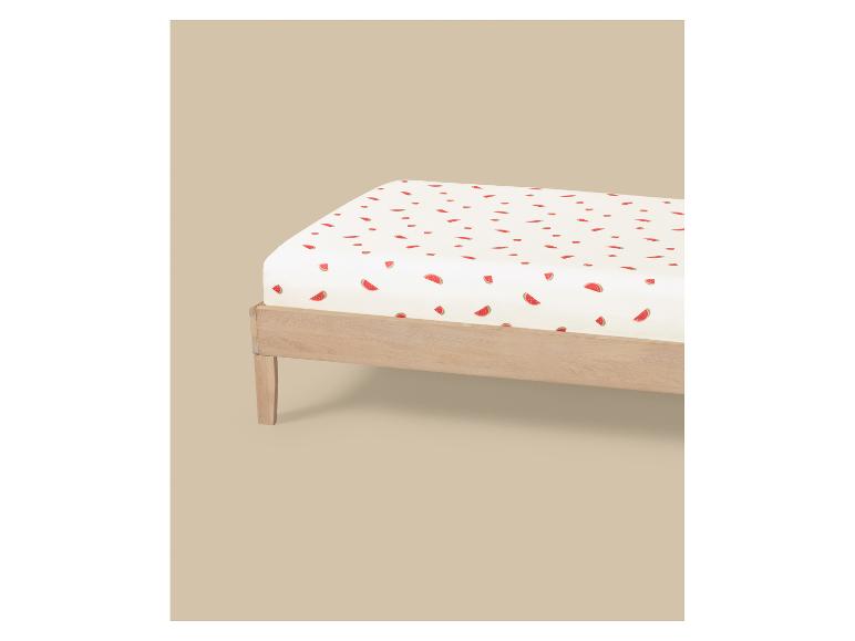 Drap blanc à motif pastèque sur un lit en bois.