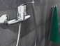Un mitigeur de douche chromé avec un tuyau sur un mur en carrelage gris.