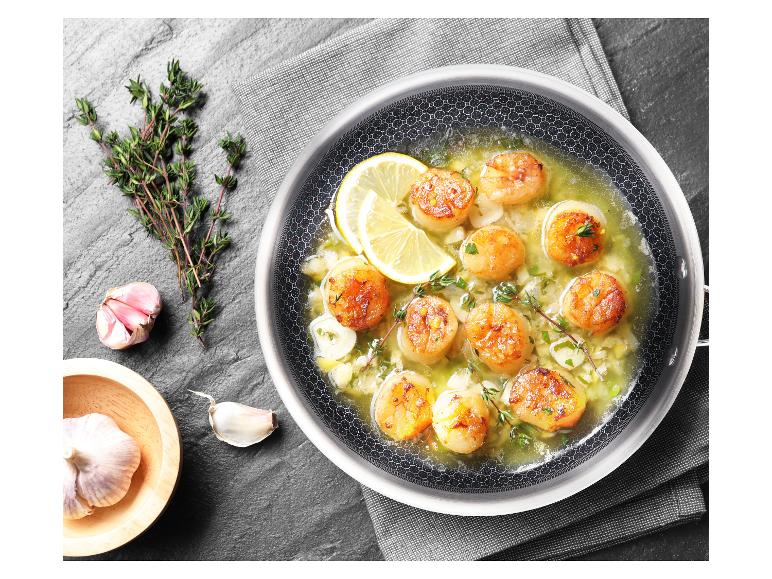 Coquilles Saint-Jacques grillées dans une poêle avec du citron et de l'ail.