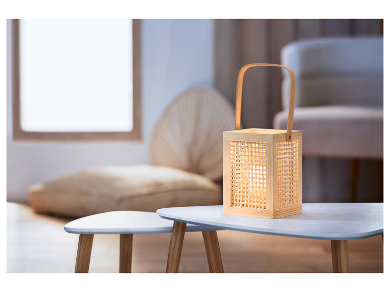 Une lampe en bois avec un motif en rotin sur une table basse blanche.