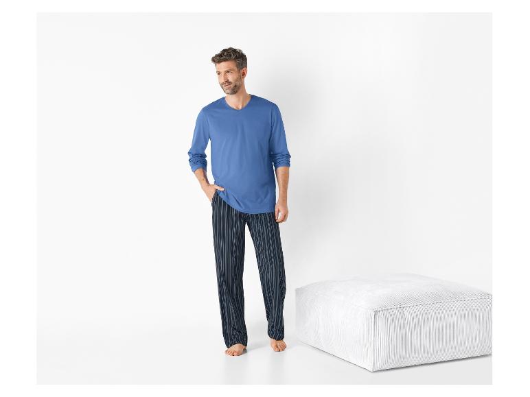 Homme portant un pyjama bleu à manches longues et un pantalon rayé.