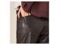 Gros plan d'une personne portant une veste marron, un pull clair et un pantalon en similicuir noir.