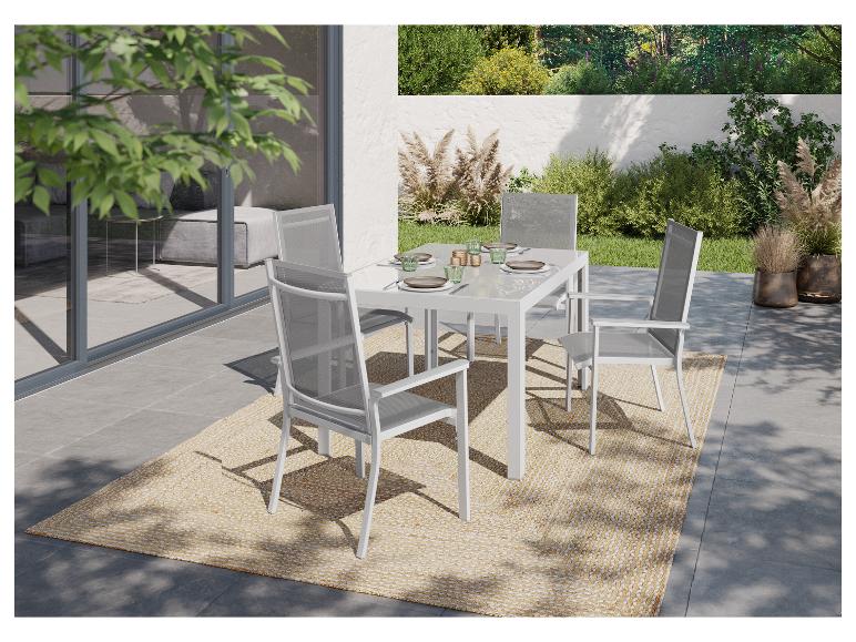 Ensemble repas extérieur : table et chaises blanches modernes sur tapis beige.