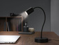 Une lampe de bureau flexible noire sur un bureau en bois.