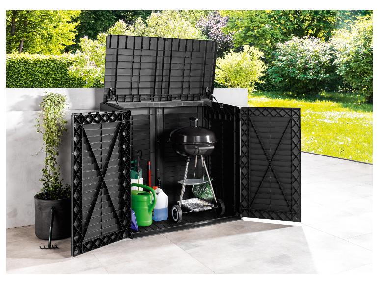 Coffre de rangement de jardin noir avec un barbecue et des outils sur une terrasse.