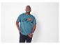 Un homme porte un t-shirt turquoise Columbia avec un motif de montagnes.