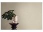 Une plante dans un vase rose clair sur un tabouret en bois foncé avec un œuf décoratif.