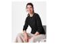 Une femme porte un pull noir à manches longues et un pantalon beige.