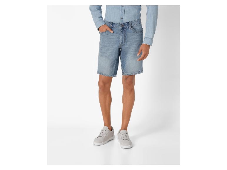 Un homme portant un short en jean bleu clair et des baskets blanches.