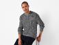 Un homme portant un pull gris avec un patch Alpha Industries.