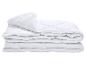 Couette blanche matelassée, pliée, sur fond blanc.