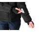 Femme en veste noire et pantalon bleu foncé, insérant une carte dans la poche de la manche.