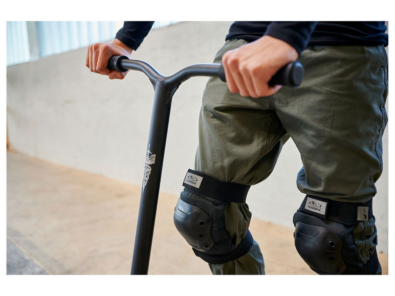 Une personne utilisant une trottinette freestyle noire avec des genouillères Hudora.