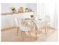 Une nappe rayée sur une table en bois avec des chaises blanches.