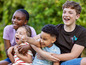 Quatre enfants rient et s'embrassent à l'extérieur.