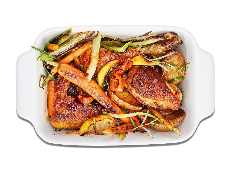 Cuisses de poulet rôties avec des pommes de terre, des carottes et des oignons verts.