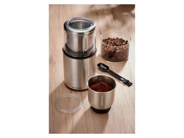 Moulin à café SilverCrest en acier inoxydable avec grains de café et café moulu.