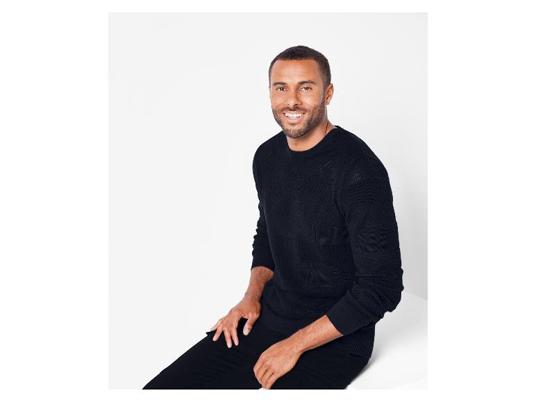 Un homme portant un pull et un pantalon noirs.