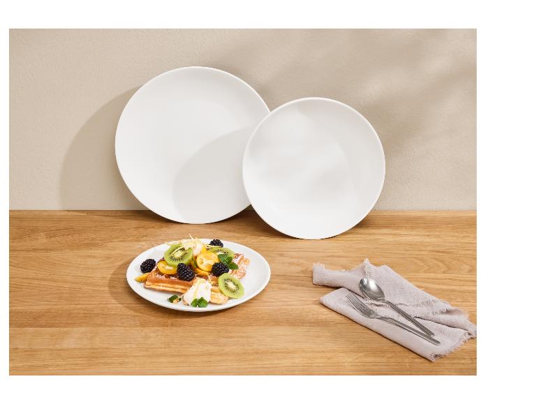 Gaufres aux fruits, deux assiettes blanches et des couverts sur une table en bois.