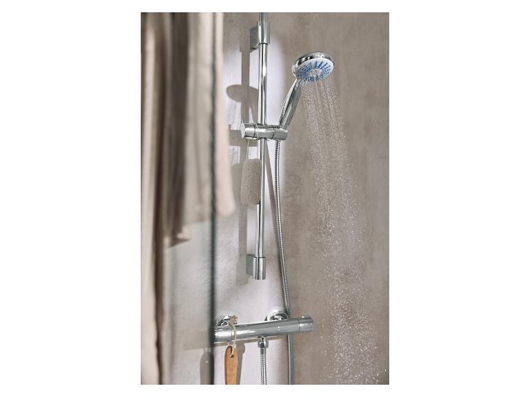 Une pomme de douche avec de l'eau qui jaillit et une éponge de bain suspendue à la barre.