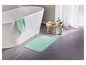 Un tapis de bain vert sur le sol.