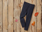 Leggings noires sur un fond en bois avec des feuilles d'automne.