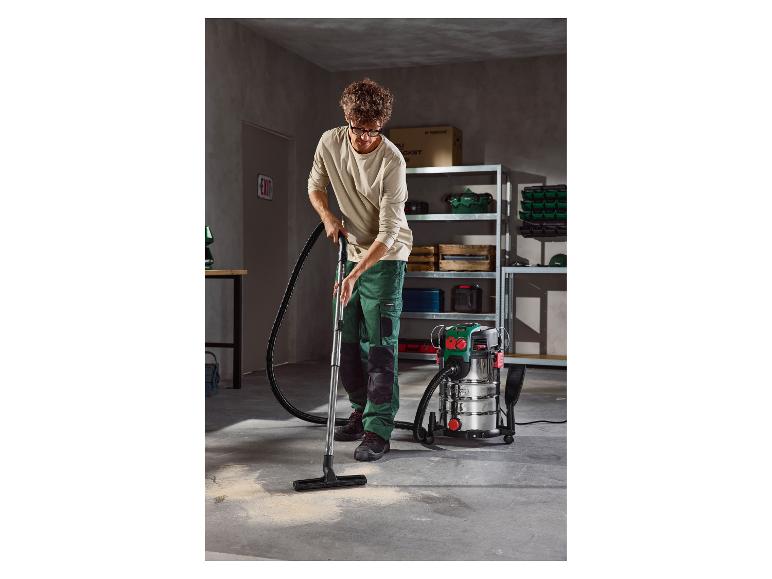 Un homme nettoie un sol de garage avec un aspirateur eau et poussière Parkside.