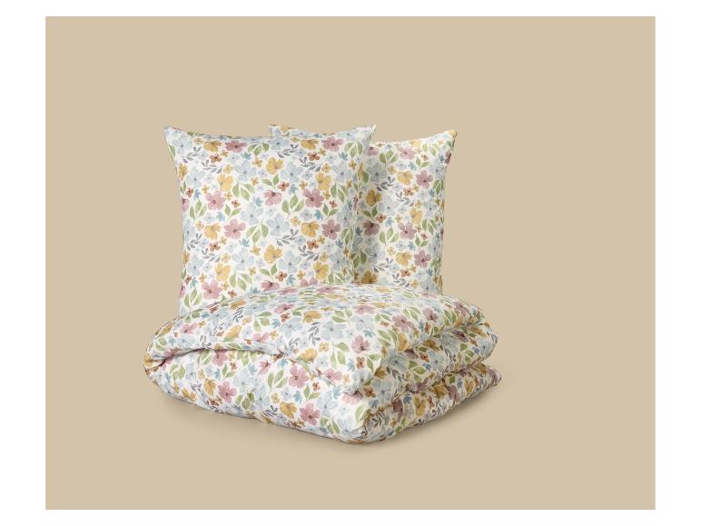 Parure de lit florale avec deux oreillers et une couette pliée.