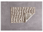 Tapis de bain beige sur sol gris.