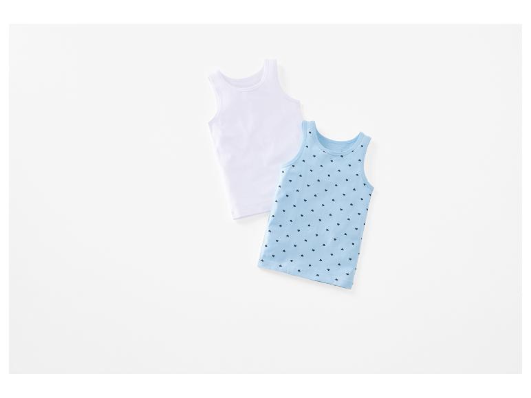 Deux débardeurs pour enfant, un blanc et un bleu clair à motifs cœurs.