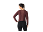 Une femme porte un haut bordeaux à manches longues et des leggings noirs.