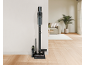 Aspirateur sans fil avec accessoires dans un salon lumineux.
