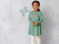 Une fille porte une robe verte à papillons et des leggings blancs à pois.