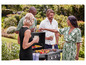 Un groupe de personnes profitent d'un barbecue avec de la nourriture grillée et des boissons dans le jardin.