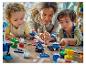Adulte et deux enfants jouent avec des briques LEGO Duplo colorées sur le sol.