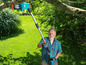 Un homme utilise une scie à élaguer télescopique Gardena dans le jardin.