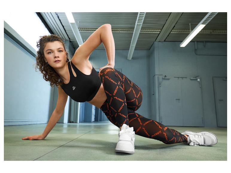 Femme en brassière de sport noire et leggings imprimés, faisant de l'exercice.