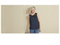 Une femme porte un top bleu marine avec une dentelle et un jean.