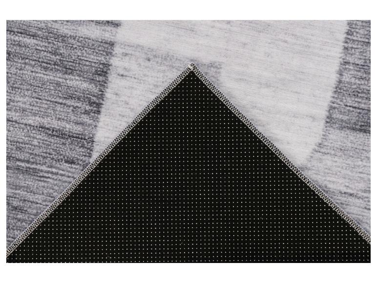 Tapis gris à motif rayé et envers antidérapant à pois blancs.