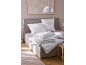 Literie blanche et couettes sur un lit dans la chambre.