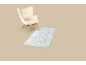 Fauteuil beige avec tapis bleu clair sur fond beige.