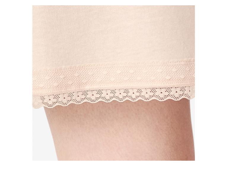 Gros plan d'une jambe de femme portant un short rose clair bordé de dentelle.