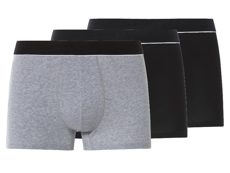 Trois boxers pour hommes: un gris, deux noirs, avec liseré blanc à la taille.