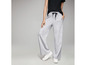 Un mannequin porte un pantalon de jogging gris avec un cordon noir et des baskets blanches.