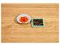 Poivron rouge coupé en dés sur une assiette blanche et un hachoir à légumes vert.