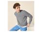 Jeune homme aux cheveux bouclés portant un pull gris côtelé et un jean bleu.