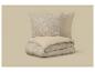 Deux oreillers et une housse de couette pliée avec un motif floral beige et uni