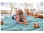 Un bébé joue avec des jouets en bois sur un tapis vert.