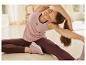 Femme en débardeur rose Kari Traa et leggings bordeaux faisant du yoga.