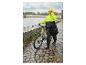 Femme portant un poncho de pluie premium CRIVIT à côté d'un vélo sous la pluie